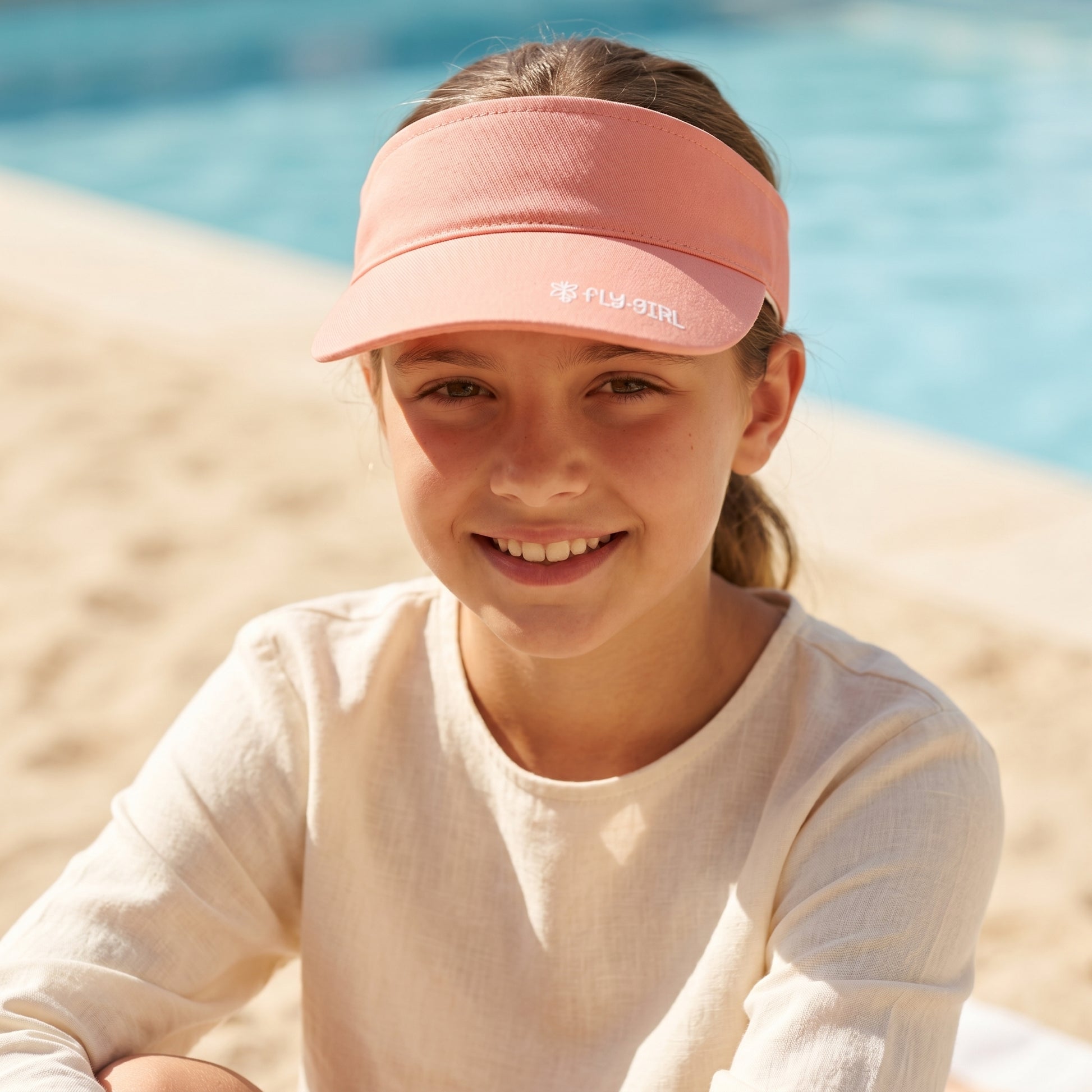 Young girl wearing a pink visor at the beach