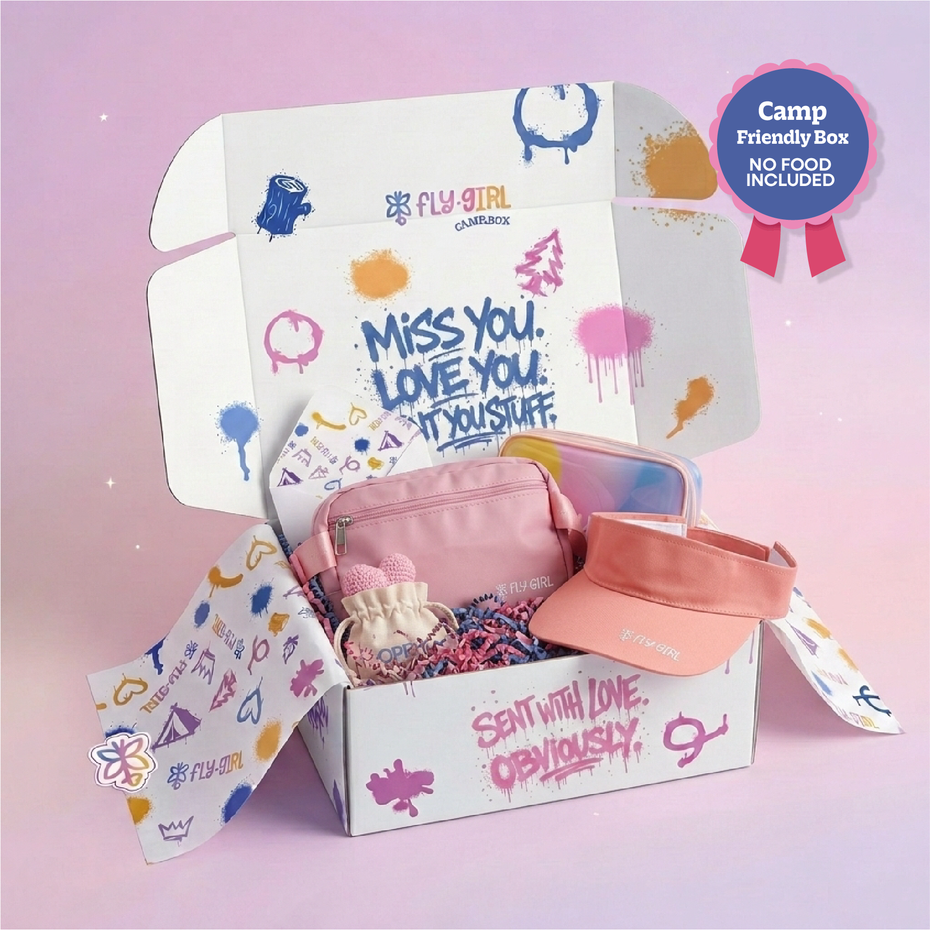 An open Fly Girl Campfire themed cardboard gift box filled with pink accessories, including a pink pouch, a peach visor, and a small plush toy, set against a soft pink background with a 'Camp Friendly Box' badge.