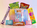 Assorted candy and snack packages on a light pink background