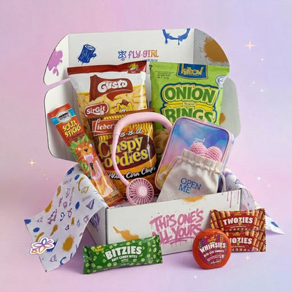 Assorted snacks and candies in a box on a pink background