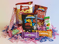 Assorted snack items including chips, candy bars, and a snack mix on a white background.