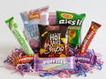 Assorted snack packages including hot sauce potato chips, candy bars, and other treats on a white background.