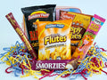 Assorted snack packages including Golden Fluff, Smorzies, and others with colorful shreds on a light blue background.
