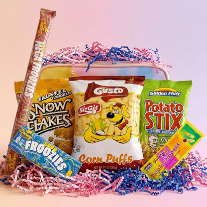A snack gift basket arrangement featuring a variety of popular candy and chip brands, including Ritz, Sizzlin' Flakes, Gusto Corn Puffs, Golden Fluff Potato Stix, and Frito-Lay Frooties, arranged in a basket lined with pink and blue paper shred on a soft pink background.