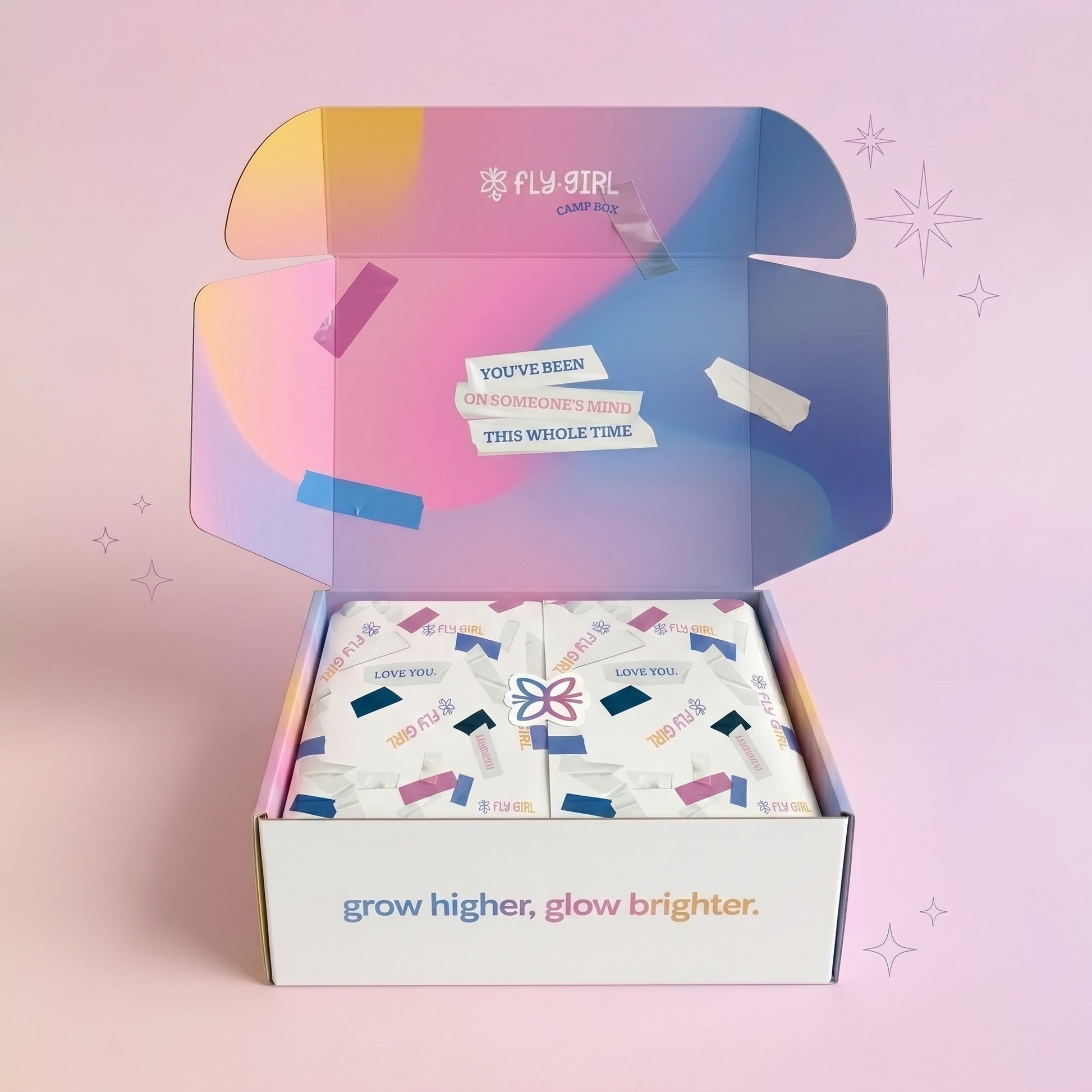 Open box with colorful packaging and 'Fly Girl' branding on a pink background