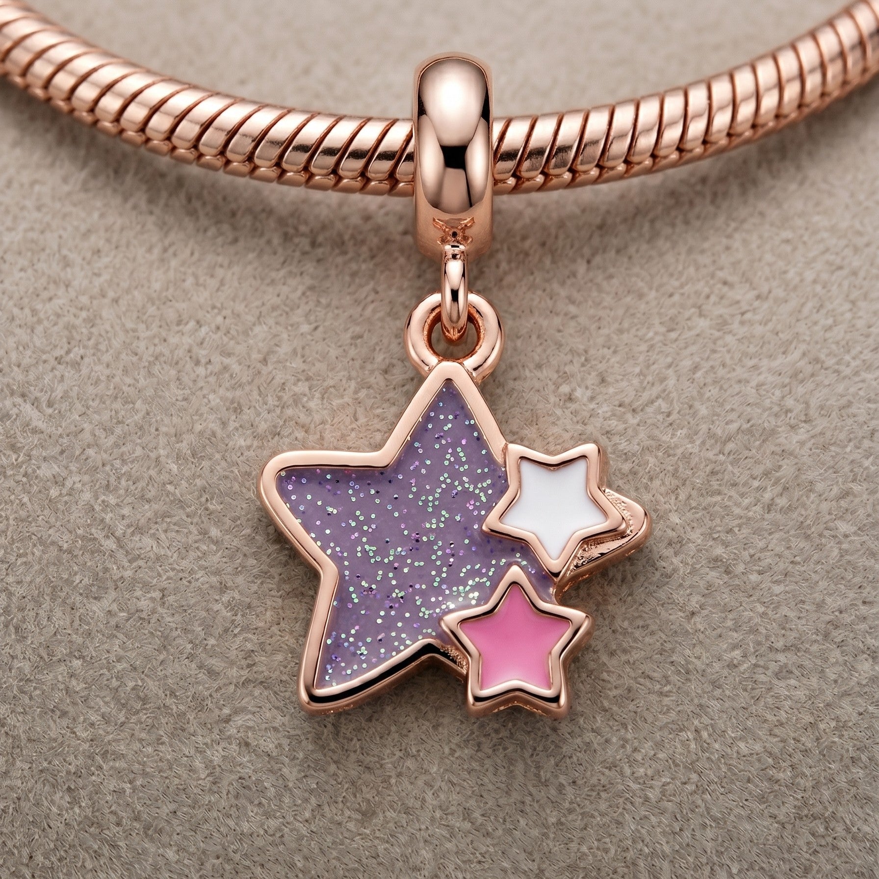 Rose gold charm with star-shaped compartments on a beige background