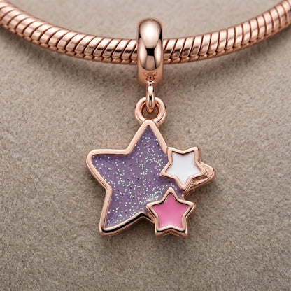 Rose gold charm with star-shaped compartments on a beige background
